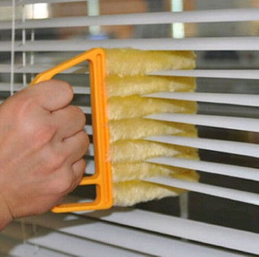 Person cleaning blinds with a yellow brush